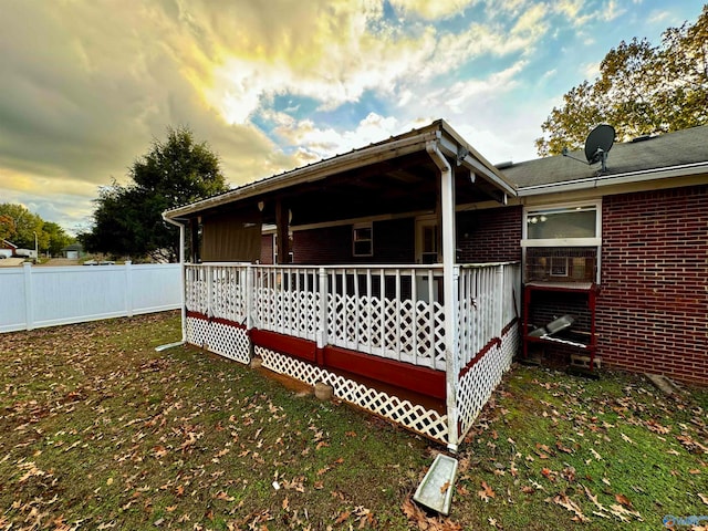 view of side of home featuring a yard, brick siding, and fence