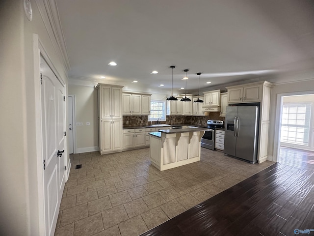 kitchen with crown molding, cream cabinets, a sink, backsplash, and stainless steel appliances