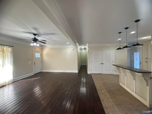 unfurnished living room featuring dark wood-type flooring, crown molding, and ceiling fan