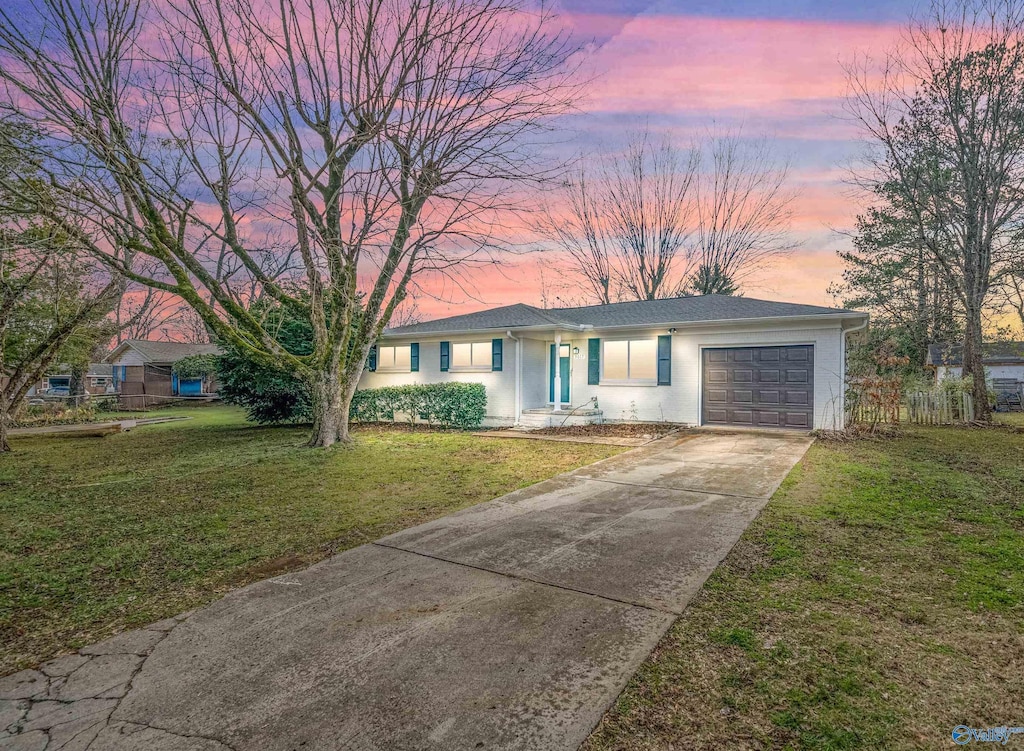 ranch-style house with a garage and a lawn