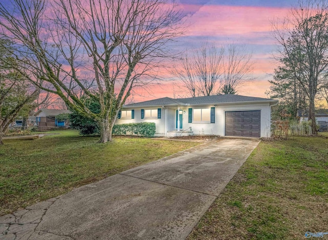 ranch-style house with a garage and a lawn