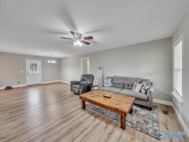 living room with baseboards, visible vents, wood finished floors, and ceiling fan with notable chandelier