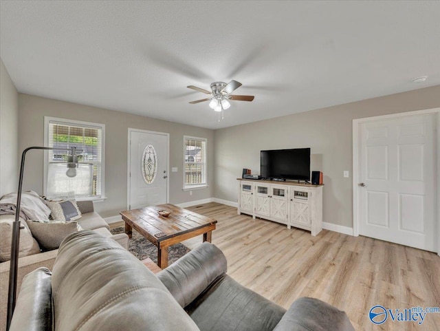living area featuring baseboards, light wood-type flooring, and a ceiling fan