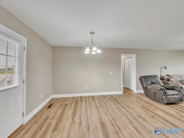interior space featuring an inviting chandelier, light wood-style floors, visible vents, and baseboards