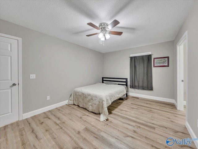 bedroom with baseboards, wood finished floors, and a textured ceiling