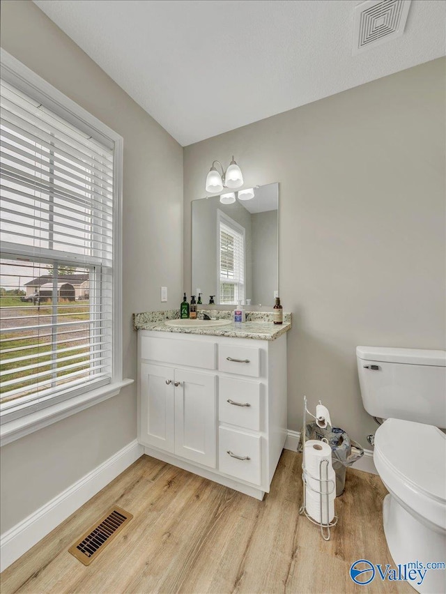 half bathroom with baseboards, visible vents, and wood finished floors