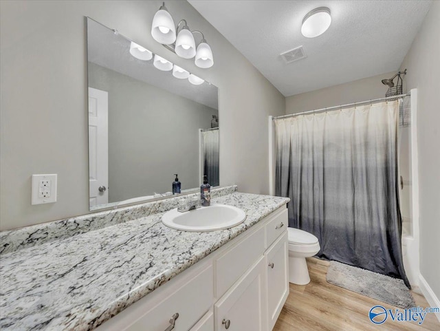 full bath with wood finished floors, shower / bath combo with shower curtain, toilet, vanity, and visible vents
