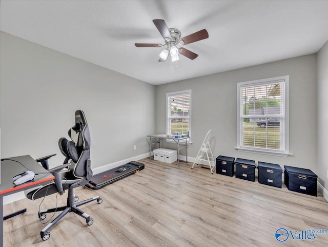 office area with a ceiling fan, a wealth of natural light, wood finished floors, and baseboards