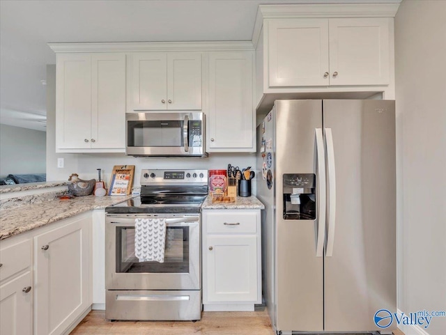 kitchen with appliances with stainless steel finishes, white cabinetry, light wood-type flooring, and light stone countertops