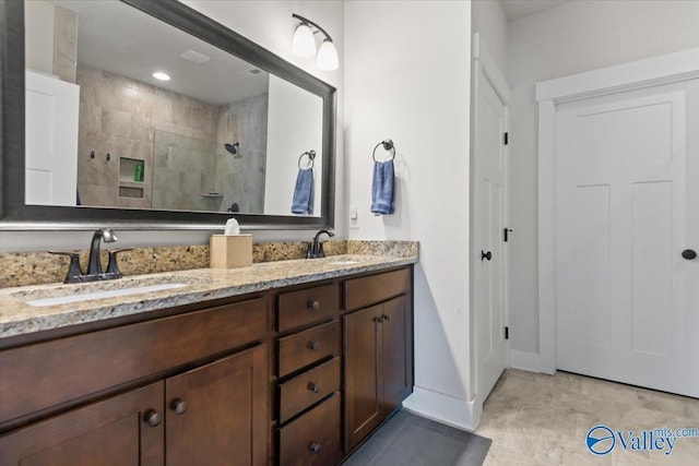 full bathroom featuring a walk in shower, double vanity, a sink, and baseboards