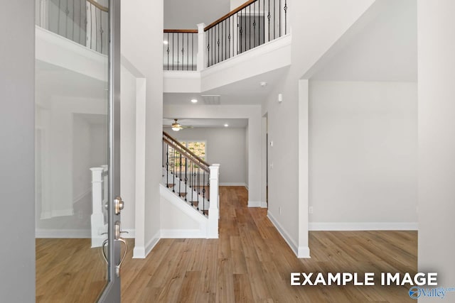 foyer entrance with ceiling fan, light hardwood / wood-style floors, and a high ceiling