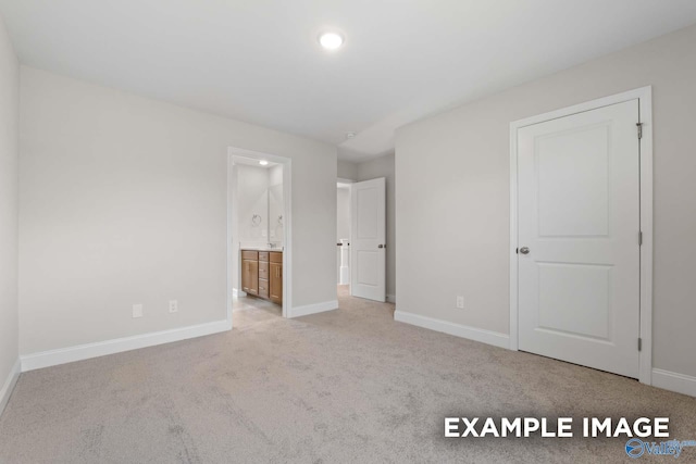 unfurnished bedroom featuring ensuite bathroom and light colored carpet