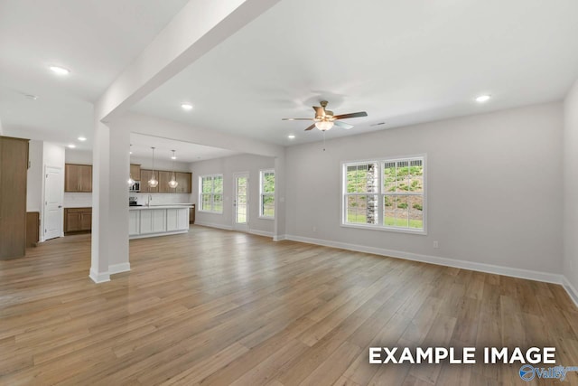 unfurnished living room with ceiling fan and light wood-type flooring