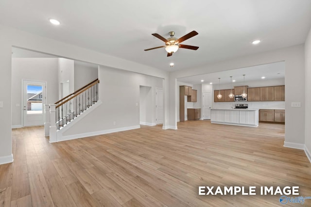 unfurnished living room featuring ceiling fan and light wood-type flooring