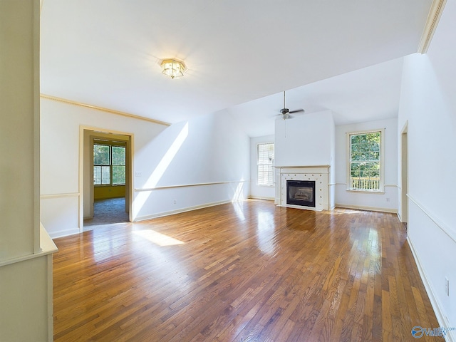 unfurnished living room featuring a tiled fireplace, ceiling fan, and wood-type flooring