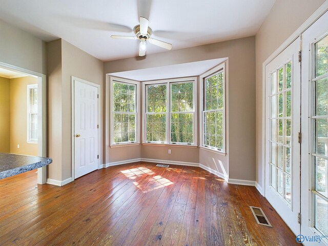 unfurnished dining area with ceiling fan, a healthy amount of sunlight, and dark hardwood / wood-style floors