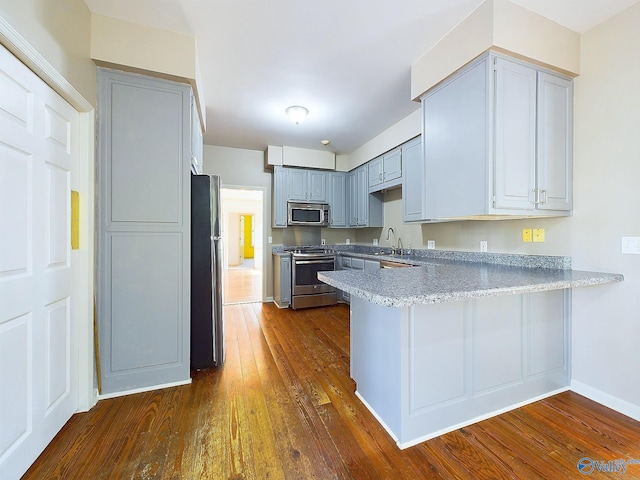 kitchen with gray cabinetry, sink, dark hardwood / wood-style floors, kitchen peninsula, and stainless steel appliances