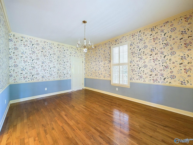 empty room featuring crown molding, hardwood / wood-style floors, and a chandelier