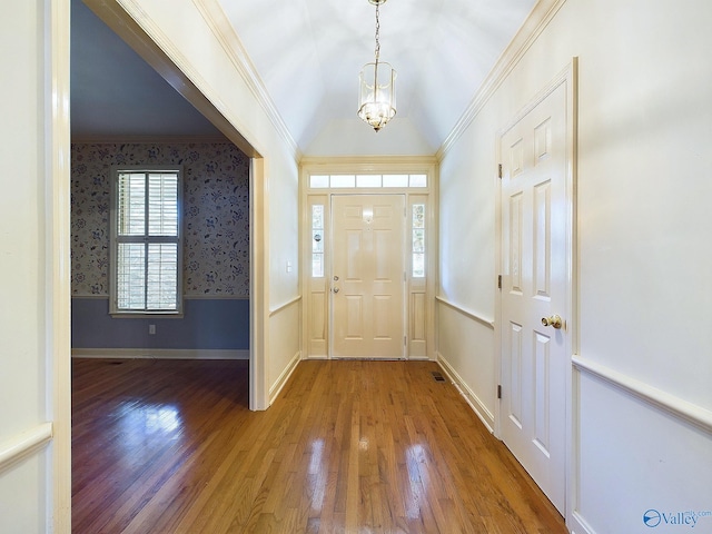 foyer with hardwood / wood-style floors, ornamental molding, and a notable chandelier