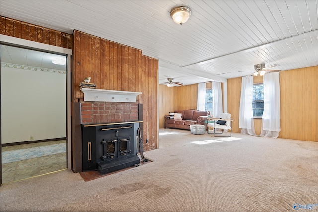 carpeted living room with a wood stove and wooden walls