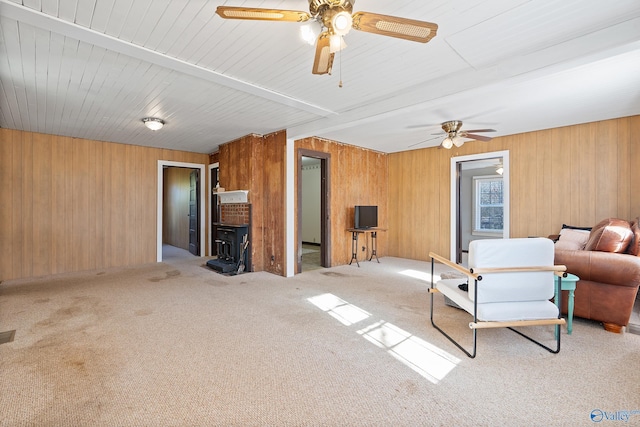 living room featuring ceiling fan, wood walls, and light colored carpet