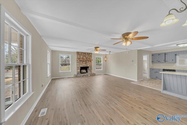unfurnished living room featuring baseboards, a fireplace, visible vents, and light wood-style floors