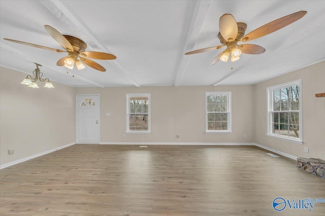 empty room featuring light wood-style floors, beam ceiling, and plenty of natural light
