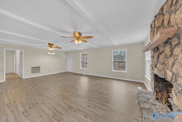 unfurnished living room with light wood-type flooring, beamed ceiling, a fireplace, and baseboards