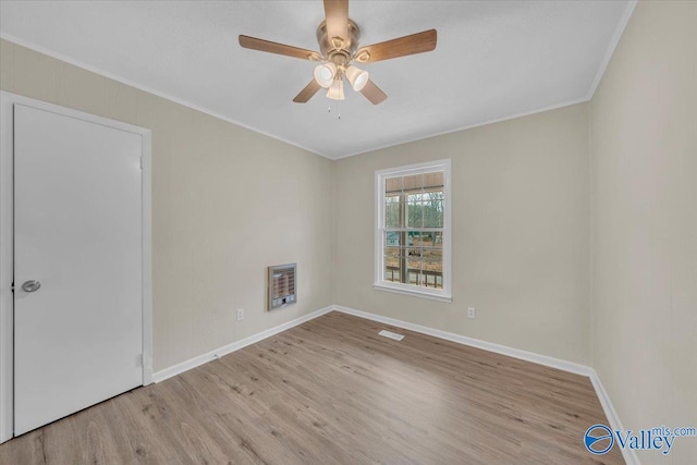 empty room featuring baseboards, ceiling fan, ornamental molding, heating unit, and light wood-type flooring