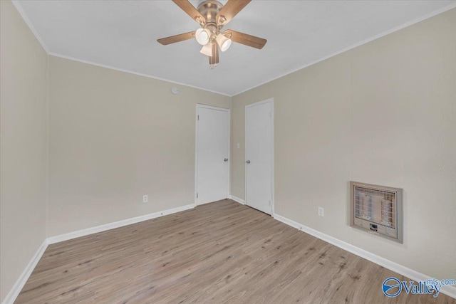 unfurnished room featuring heating unit, light wood-type flooring, baseboards, and crown molding