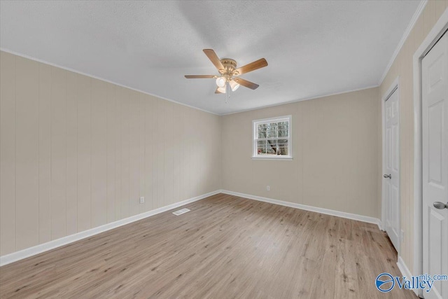 unfurnished bedroom featuring a textured ceiling, visible vents, baseboards, ornamental molding, and light wood finished floors