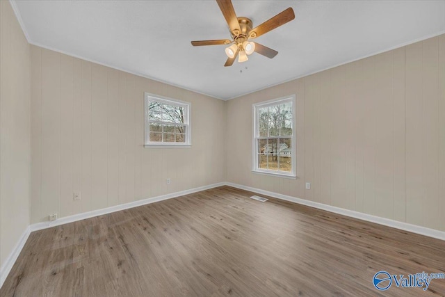 empty room featuring light wood-style floors, baseboards, visible vents, and a ceiling fan
