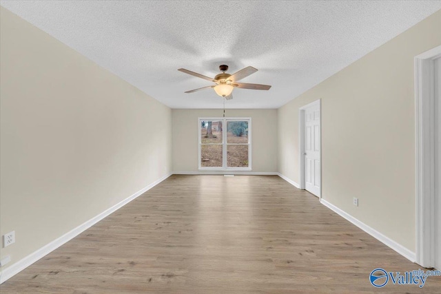 empty room featuring light wood-type flooring, ceiling fan, a textured ceiling, and baseboards