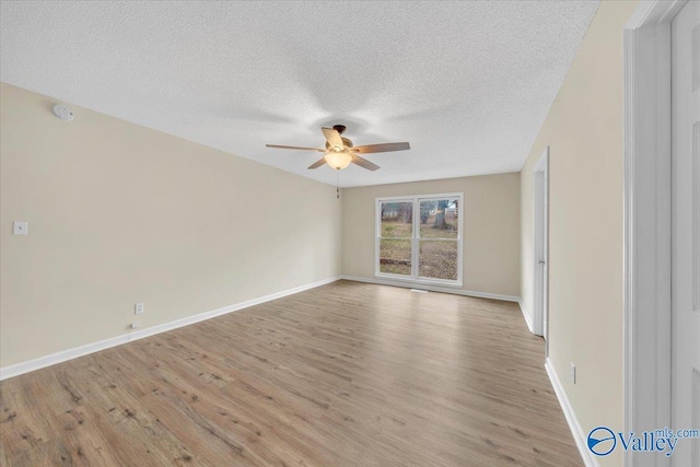 unfurnished room featuring light wood-style floors, ceiling fan, a textured ceiling, and baseboards
