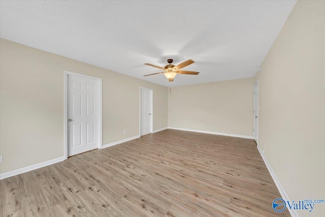 spare room with light wood-type flooring, ceiling fan, a textured ceiling, and baseboards
