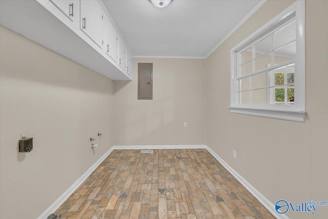clothes washing area featuring ornamental molding, electric panel, cabinet space, and baseboards