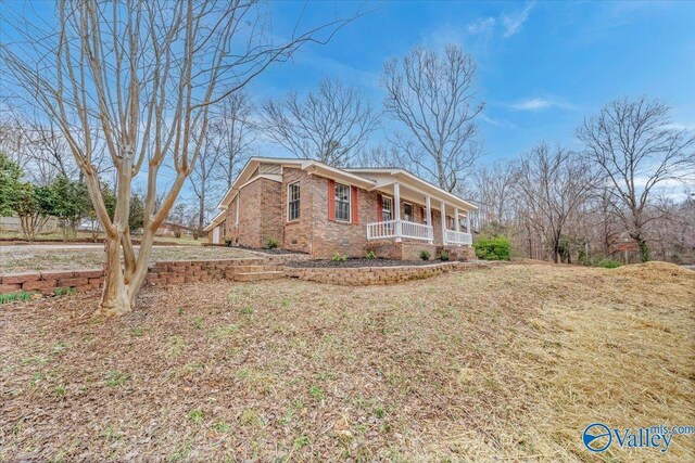 view of front of house featuring a porch, crawl space, brick siding, and a front lawn