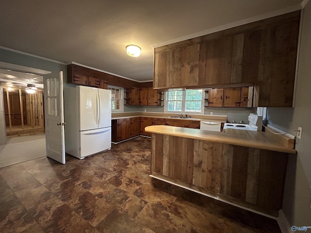 kitchen with a peninsula, light countertops, crown molding, and freestanding refrigerator