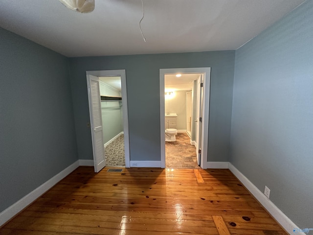 unfurnished bedroom with a closet, wood-type flooring, and baseboards