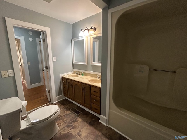 bathroom featuring baseboards, a sink, toilet, and double vanity