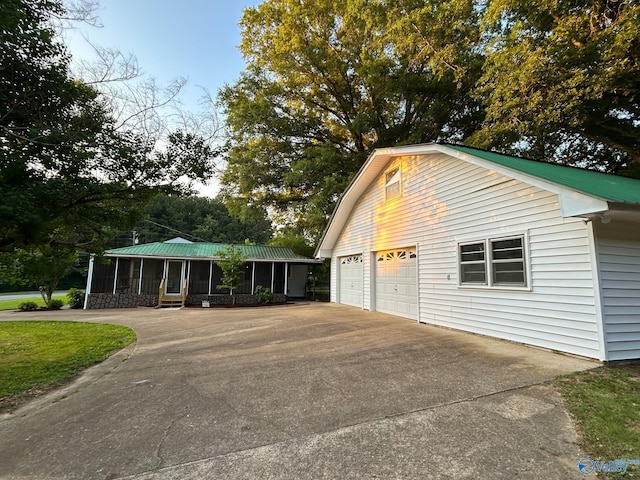 view of side of home featuring a sunroom, metal roof, and a detached garage