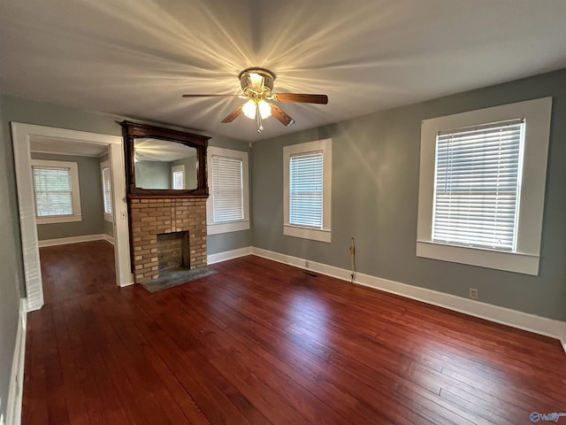 unfurnished living room featuring a brick fireplace, visible vents, baseboards, and dark wood-type flooring
