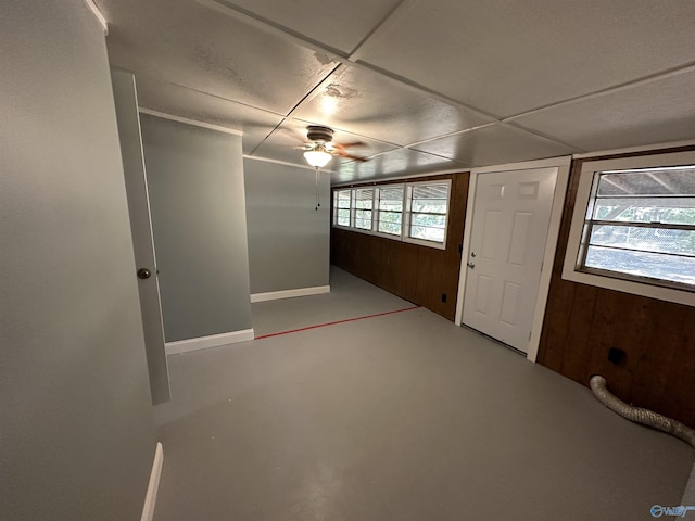 interior space featuring wood walls and a ceiling fan
