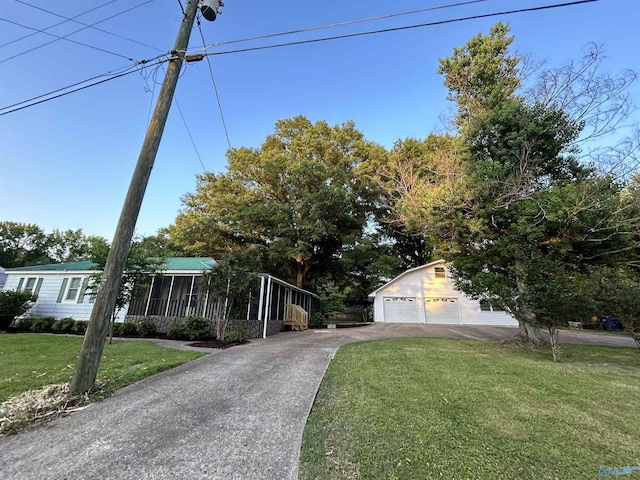 view of front facade with an outbuilding, a front lawn, a detached garage, and a sunroom