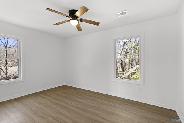 unfurnished room featuring plenty of natural light, dark hardwood / wood-style floors, and ceiling fan