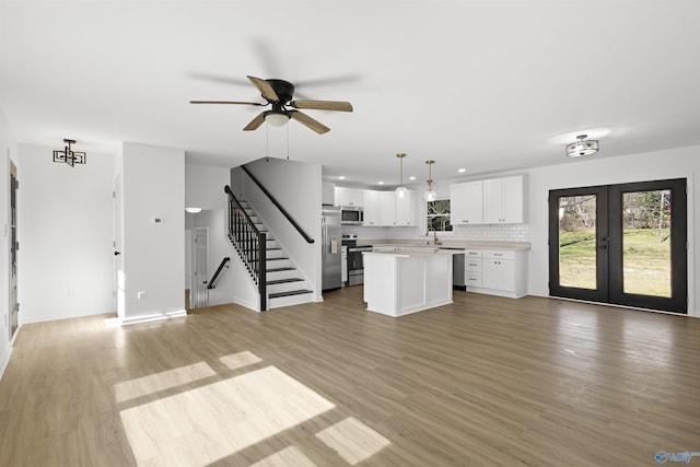 unfurnished living room with french doors, ceiling fan, sink, and light hardwood / wood-style floors