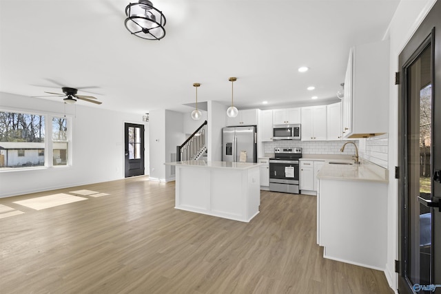 kitchen with sink, decorative light fixtures, appliances with stainless steel finishes, white cabinets, and backsplash