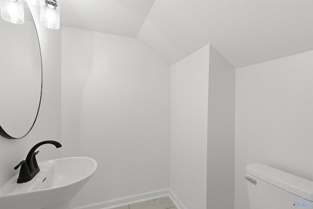 bathroom featuring lofted ceiling, toilet, and sink