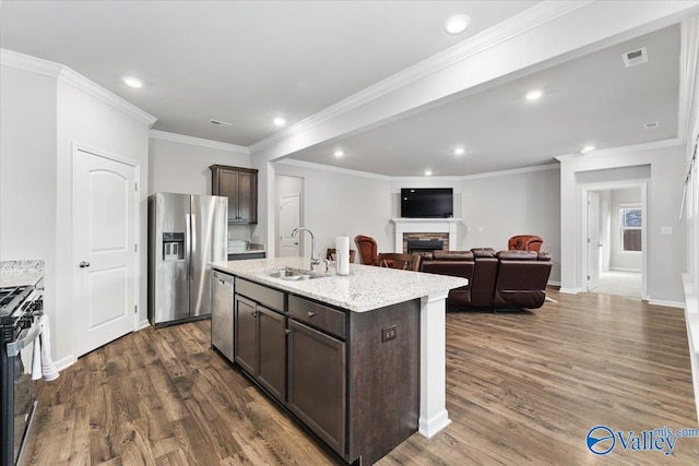 kitchen with dark wood-type flooring, sink, a kitchen island with sink, dark brown cabinets, and appliances with stainless steel finishes