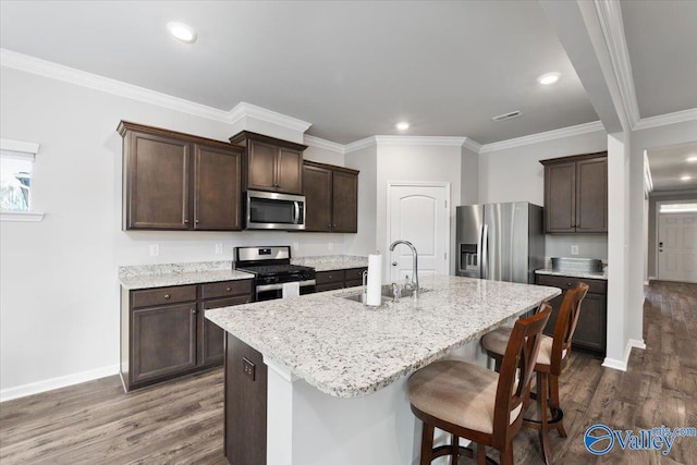 kitchen featuring dark wood-type flooring, appliances with stainless steel finishes, sink, and an island with sink